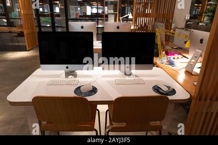 Moderna postazione di lavoro per ufficio con computer Apple iMac su un tavolo bianco in legno - spazio creativo e lavoro Foto Stock