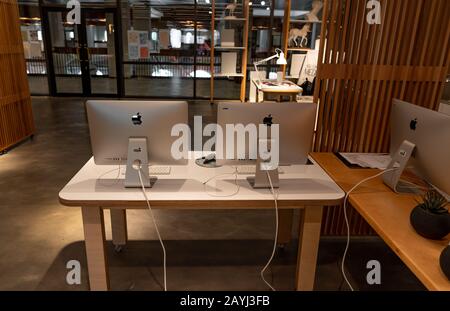 Moderna postazione di lavoro per ufficio con computer Apple iMac su un tavolo bianco in legno - spazio creativo e lavoro Foto Stock