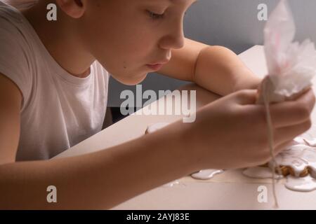 Un ragazzo di 10 anni smala i biscotti con una borsa culinaria. Fatto A Mano. Creatività dei bambini Foto Stock