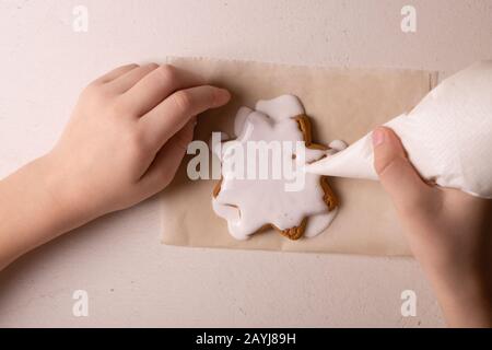 Un ragazzo di 10 anni smala i biscotti con una borsa culinaria. Fatto A Mano. Creatività dei bambini Foto Stock