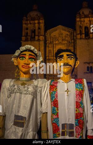 Marionette giganti vestite da sposa e sposo durante una calenda, una processione per le strade del centro di Oaxaca, celebrando un matrimonio nella città di Foto Stock