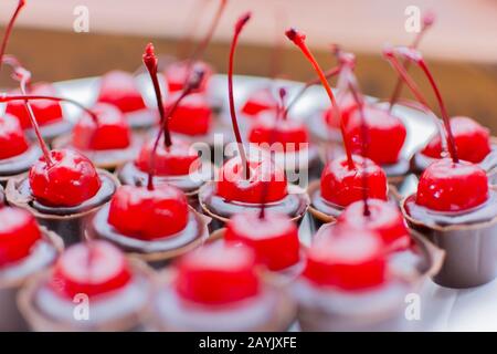 Piatto bianco con molte tazze di cioccolato ricoperte di ciliegia. Festa di compleanno caramella closeup. Messa a fuoco selettiva. Deliziosa caramella da festa, dolci da festa, re Foto Stock