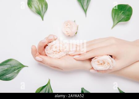 Bella elegante manicure rosa femmina alla moda con fiore sullo sfondo, vista dall'alto. Concetto bio natura cosmetici cura della pelle Foto Stock