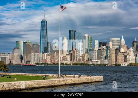 New YORK, USA - 10 OTTOBRE: Vista della bandiera americana su Ellis Island con lo skyline della città lungo il fiume Manhattan in lontananza il 10 ottobre 2019 a New Foto Stock