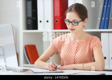 Donna in ufficio prende appunti in un diario Foto Stock