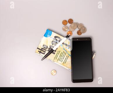 Telefono, denaro, penna e carta piegata su sfondo grigio. Vista dall'alto. Primo piano. Foto Stock