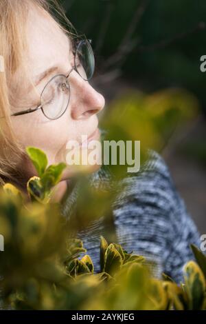 Donna anziana con occhi chiusi gode fuori con il viso verso il sole. Donna anziana con occhiali Foto Stock