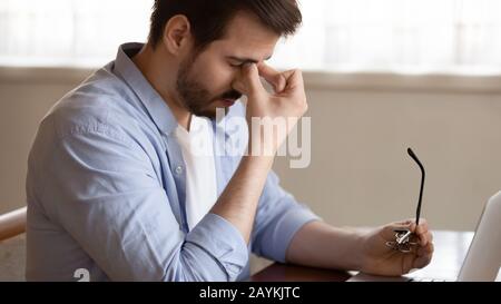 L'uomo stanco togliere gli occhiali che soffrono di mal di testa Foto Stock