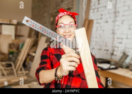 Donna professionale lavora con il legno e misura con un angolo righello Foto Stock