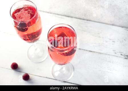 Kir Royal Champagne cocktail su bianco, copia spazio. Flute bicchieri con champagne frizzanti per celebrare o raffreddare. Foto Stock