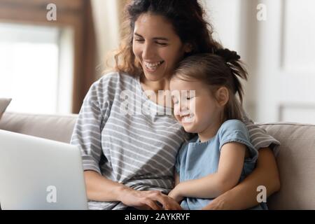 Felice giovane madre guardando divertenti cartoni animati sul computer con figlia. Foto Stock