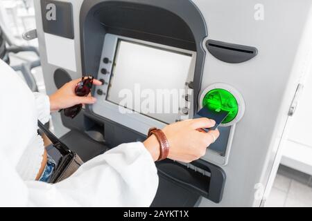 Donna che ritira denaro utilizzando carta bancaria di plastica al bancomat. Concetto di finanza e flusso di cassa Foto Stock