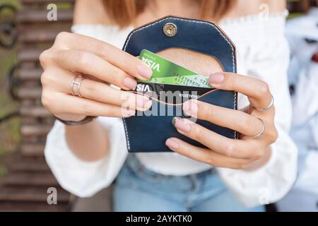 La ragazza tira fuori le carte di credito di plastica dalla sua borsa. I giovani scelgono il denaro elettronico su un conto bancario non in contanti piuttosto che in contanti Foto Stock