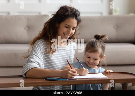 Gioioso giovane mummia disegno immagini cute con figlia adorabile. Foto Stock