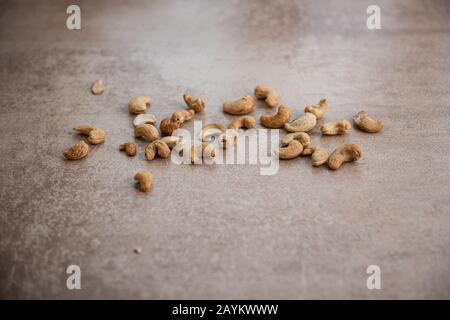 un sacco di noci di anacardi fritti sparsi su sfondo grigio con spazio per la copia Foto Stock