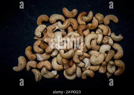 un sacco di noci di anacardi fritti sparsi su sfondo grigio con spazio per la copia Foto Stock