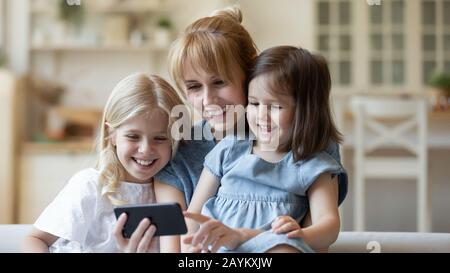 Mamma e figlie giovani felici hanno divertimento utilizzando la cella Foto Stock