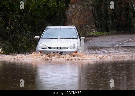 Sidmouth, Devon, Regno Unito. 16th febbraio 2020. Meteo Regno Unito. Un'auto guida anche se inondare l'acqua da pioggia pesante da Storm Dennis sulla B3176 vicino a Sidmouth nel Devon. Foto Di Credito: Graham Hunt/Alamy Live News Foto Stock