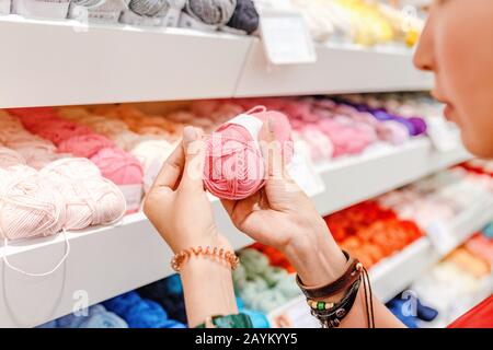 Donna scegliere filati e palle di lana per l'acquisto in negozio di artigianato Foto Stock