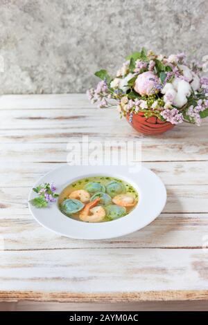 Gnocchi di zuppa e gamberetti serviti con porri. Su vecchio sfondo bianco di legno. Foto Stock