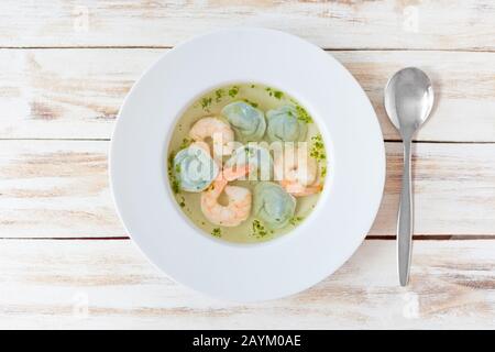 Gnocchi di zuppa e gamberetti serviti con porri. Su vecchio sfondo bianco di legno. Foto Stock