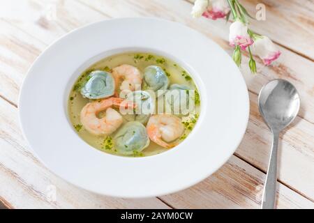 Gnocchi di zuppa e gamberetti serviti con porri. Su vecchio sfondo bianco di legno. Foto Stock