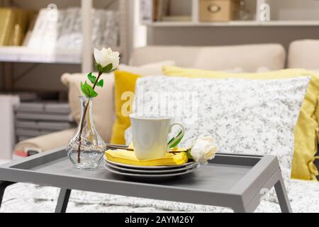 Vassoio grigio in legno con caffè e fiori, arredamento interno sul letto. Colazione romantica in stile bed. Foto Stock