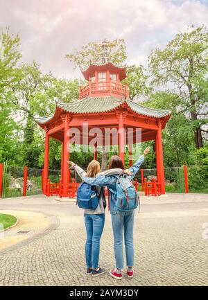 Due giovani donne abbracciano e ammirano la vista dell'architettura cinese della pagoda, un viaggio verso l'est concetto Foto Stock