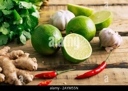 Cibo tailandese, lime, zenzero, peperoncino, aglio e coriandolo su sfondo di legno Foto Stock