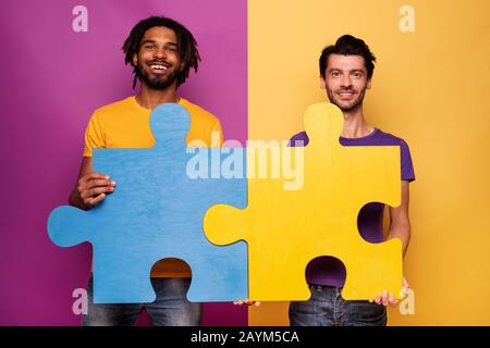 Gli amici di enigmi in mano su sfondo giallo. Concetto di integrazione europea e il partenariato Foto Stock