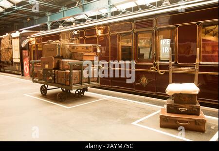 Foto d'epoca delle valige sulla piattaforma accanto al vecchio treno a vapore (locomotiva) Foto Stock