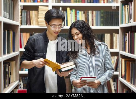 Coppia multiculturale sorridente in piedi presso la biblioteca moderna Foto Stock