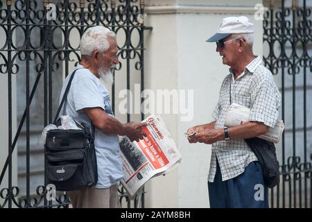 Due cubani con il giornale granma all'Avana. Due persone parlano mentre tengono uno dei giornali cubani Foto Stock