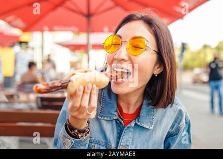 Donna che mangia Currywurst fast food salsiccia tedesca in bar all'aperto Street food Foto Stock