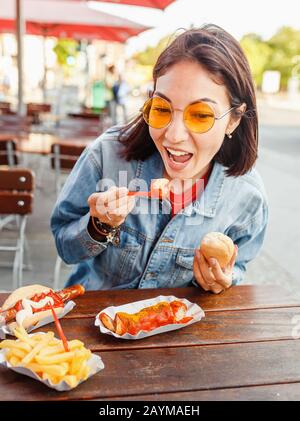 Donna che mangia Currywurst fast food salsiccia tedesca in bar all'aperto Street food Foto Stock