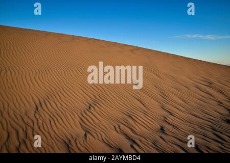 Paesaggio astratto di dune di sabbia testurizzata con cielo blu e nube di luce. Preso al parco naturale di Correlejo a Fuerteventura, Spagna. Foto Stock