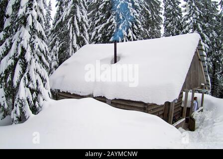 piccola casa in inverno montagne tra la foresta innevata Foto Stock