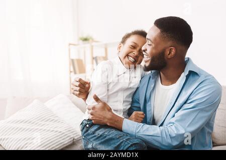 Emozioni autentiche. Il papà africano solletico figlia carina Foto Stock