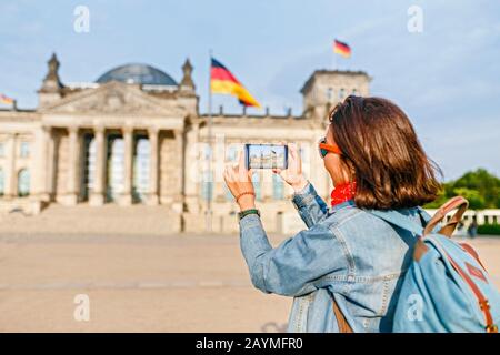 Bella giovane donna in abbigliamento casual scattare foto dal suo telefono cellulare al Bundestag, Berlino Foto Stock