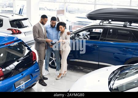 Coppia Acquistare Una Nuova Vettura Scegliendo Auto Con Manager In Concessionaria Foto Stock