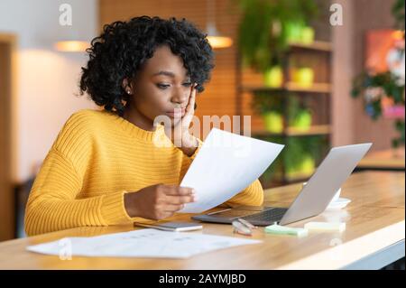 Concentrato afro girl editor lavorare con il testo al caffè Foto Stock