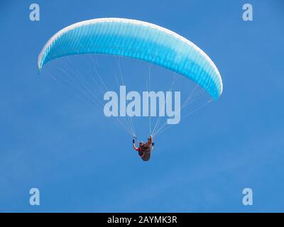Un uomo vola nel suo parapendio davanti al cielo blu Foto Stock