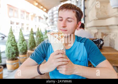 L'uomo che mangia Doner Kebap la sua cucina orientale media fast food Foto Stock