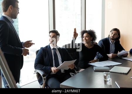 Sorridente businesswoman afroamericano che alza la mano chiedendo mentore in consiglio di amministrazione. Foto Stock