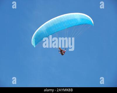 Un uomo vola nel suo parapendio davanti al cielo blu Foto Stock