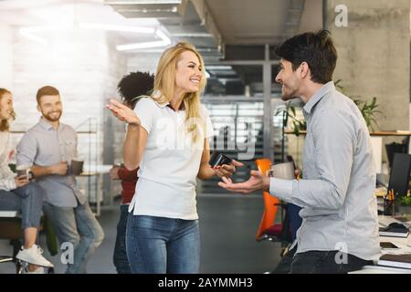 Giovani colleghi amichevoli che hanno conversato sul posto di lavoro Foto Stock