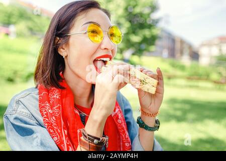 Giovane donna mangiare sandwich e fare una pausa pranzo all'aperto nel parco Foto Stock