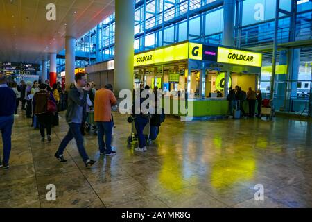 Noleggio auto Goldcar presso l'aeroporto di Alicante con coda di turisti Foto Stock