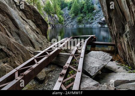 Rotaie di una gru rotta, che conduce verso il lago di Hodge Close Quarry, un ex miniera di ardesia, Lake District, Cumbria, Inghilterra, Regno Unito Foto Stock