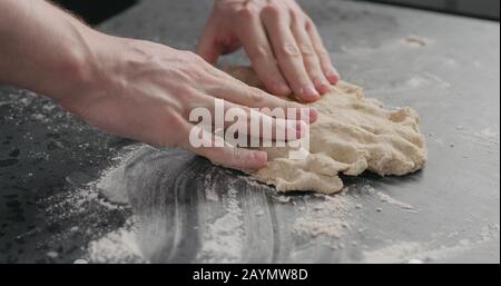 l'uomo aggiunge olio di oliva alla pasta sul ripiano in cemento, foto larga Foto Stock